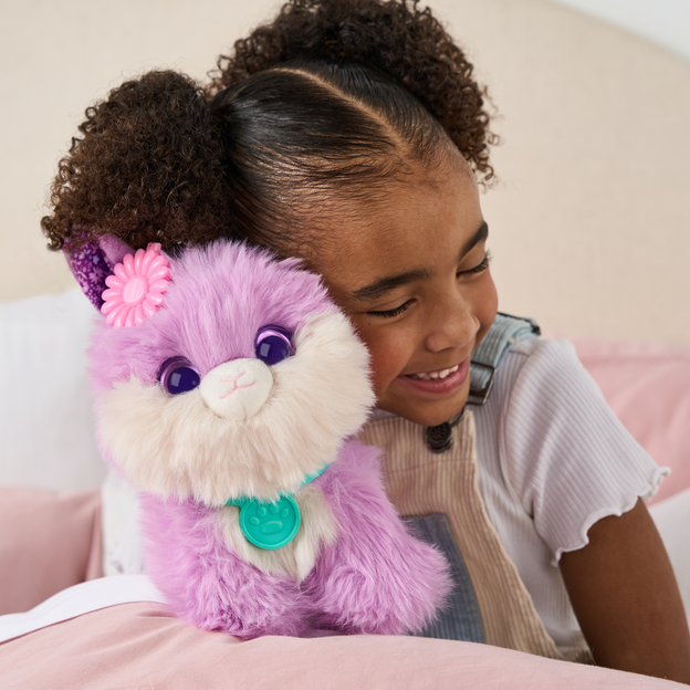 Young girl pressing her cheek against a purple ScruffaLuvs toy. 