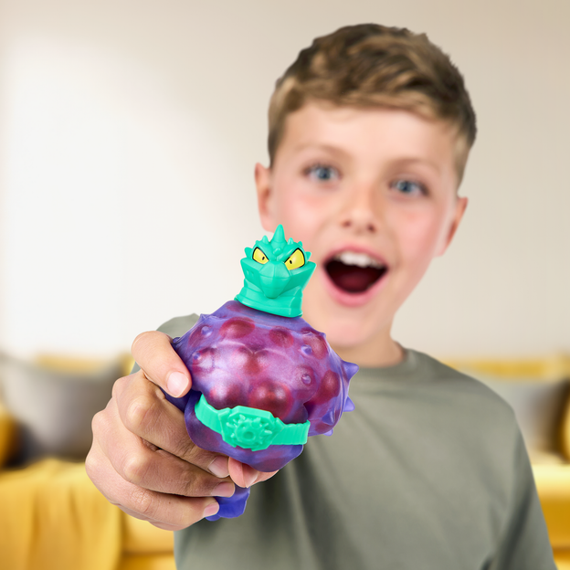 Young boy squeezing a purple Heroes of Goo Jit Zu toy with a red marble goo filling. 