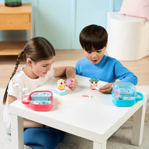 Young boy and girl playing with their Ouchies vet kits on a table. 