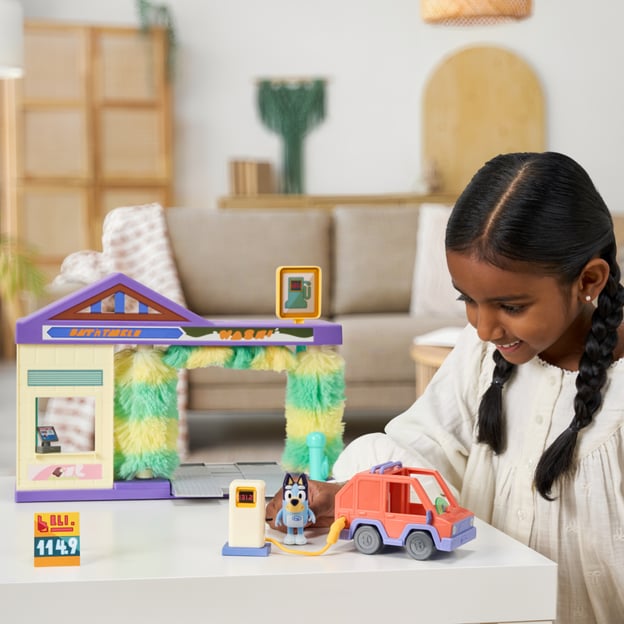 Young girl playing with a Bluey Car Wash playset. 