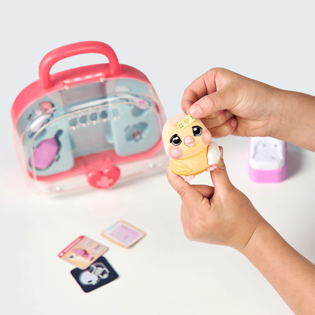 Two hands holding a little yellow bird toy and placing a band aid on its forehead. 