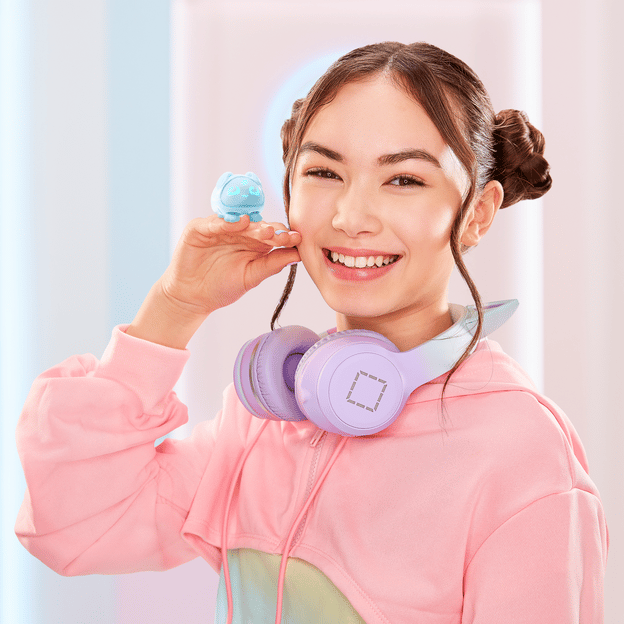 Young girl smiling at camera holding her hand up to her face with a blue micropet toy sitting on the back of her hand.