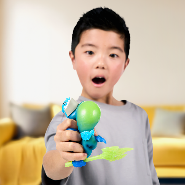 Young boy squeezing a blue Heroes of Goo Jit Zu toy with green filling bursting out. 