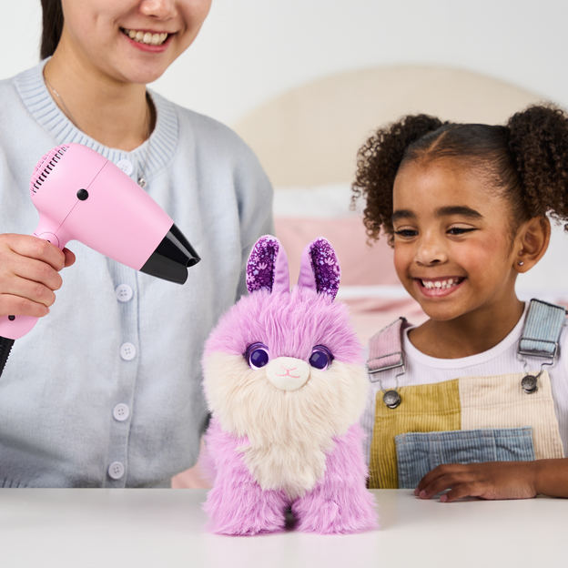 Mother and daughter blow drying a purple ScruffaLuvs toy. 
