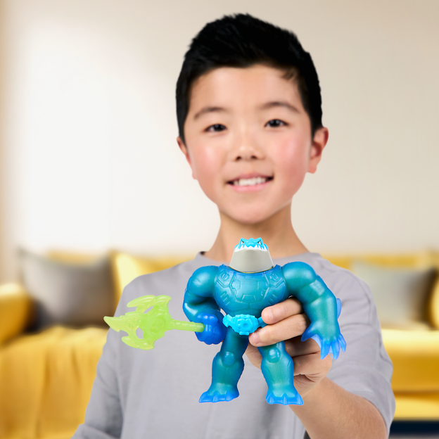 Young boy holding his blue Heroes of Goo Jit Zu action figure with a green trident. 