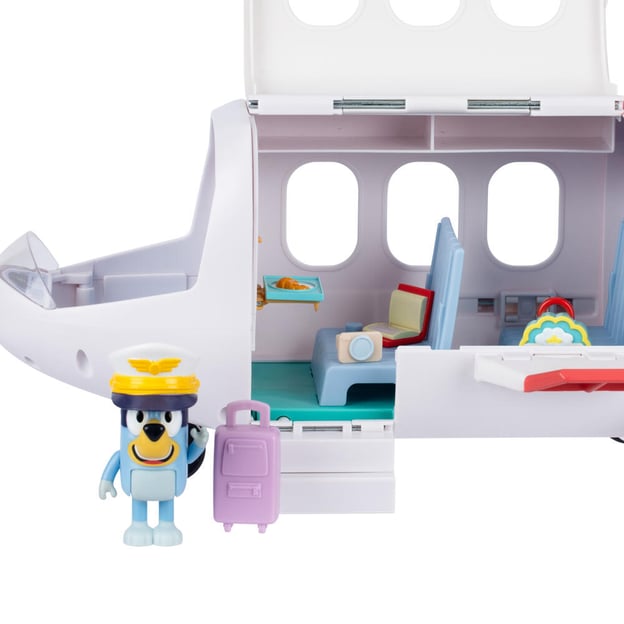 Bluey's jet toy out of packaging with Bluey figurine standing in front next to purple suitcase. 