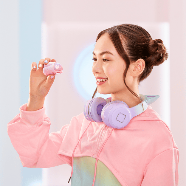 Young girl smiling, facing the left, holding up pink micropet toy. The toy matches her pink jumper