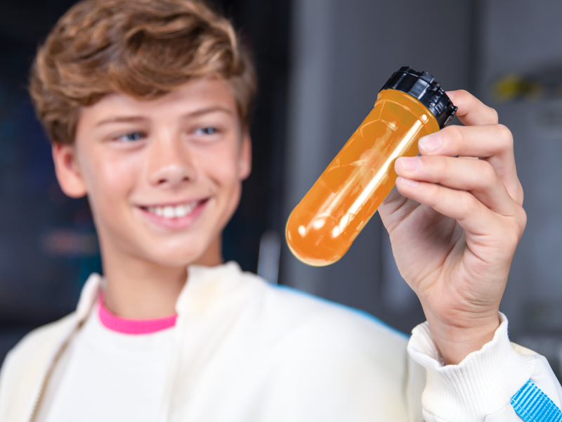 Boy shaking an orange test tube.