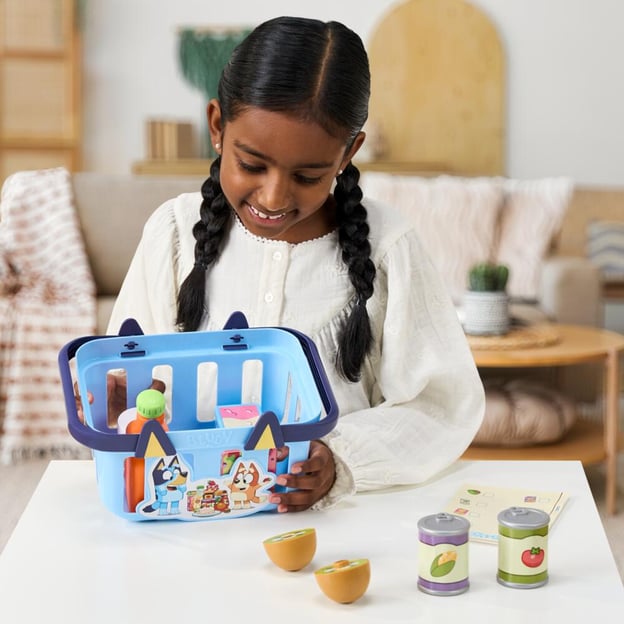 Young girl holding a Bluey Role-Play Shopping Basket toy.