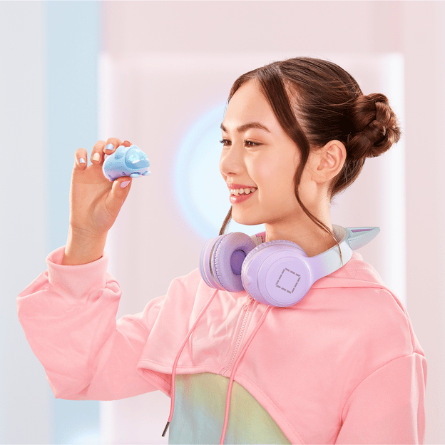 Young girl facing the left, smiling and holding up a blue micropet toy.