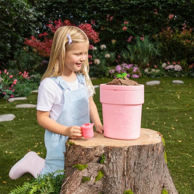 Little girl watching her Luvibubs Doll Single Pack Brave Bella pop out of a pink pot. 