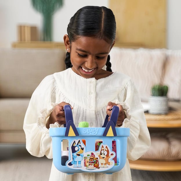 Young girl holding a Bluey Role-Play Shopping Basket toy in her hands.