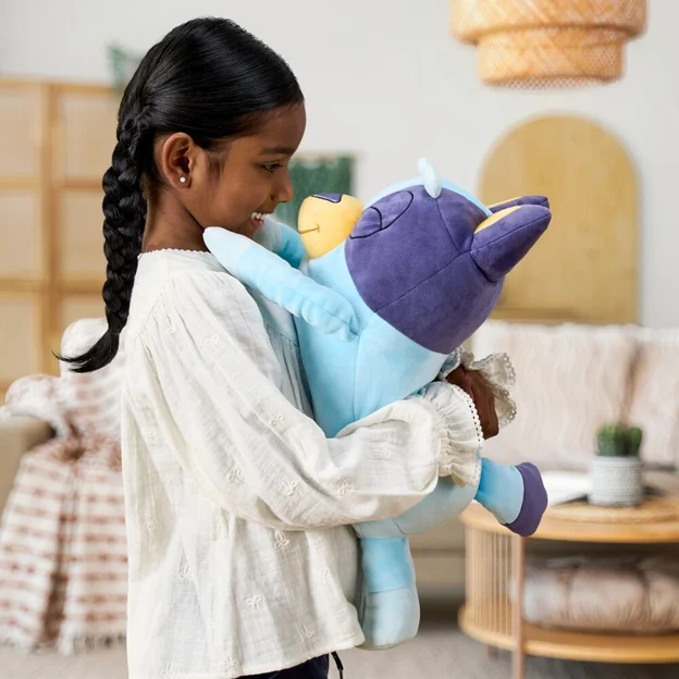 Little girl cuddling a sleepy Bluey plush.