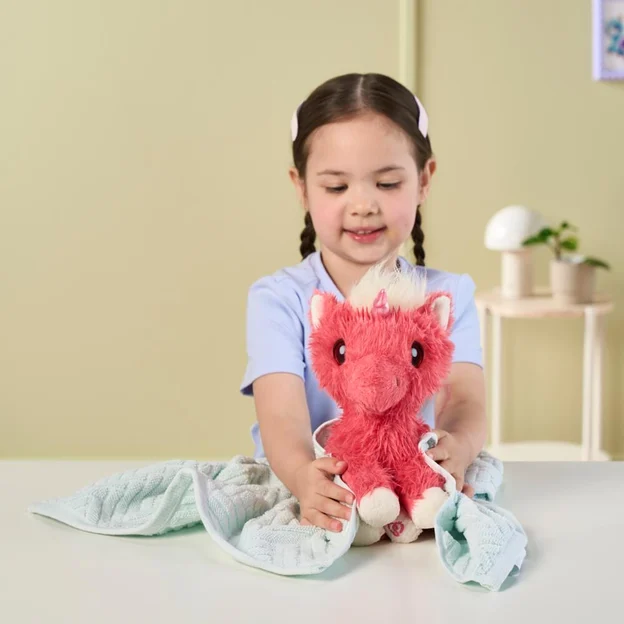 Young girl drying a ScruffaLuvs Coral Pet toy with a towel.