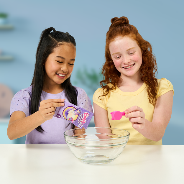 Two young girls pouring ingredients into a glass bowl.