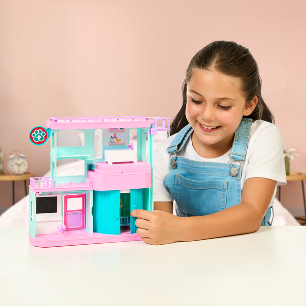 Little girl closing the curtains of her Mam Surprise Families Playset. 