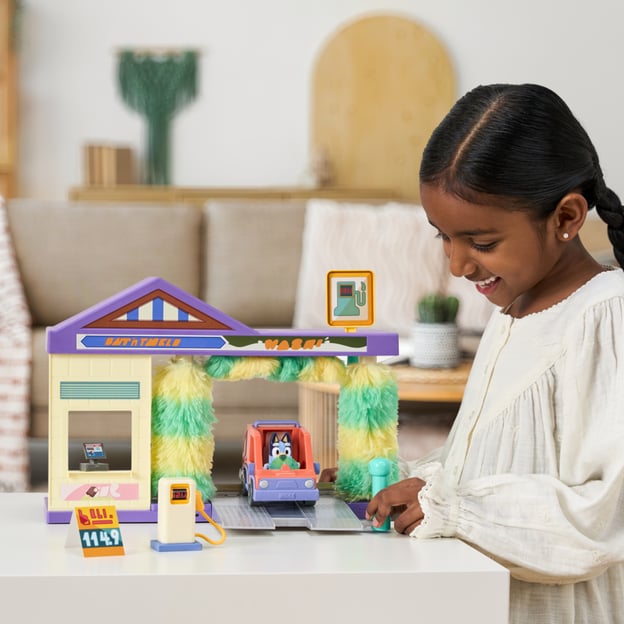 Young girl playing with a Bluey Car Wash playset. 