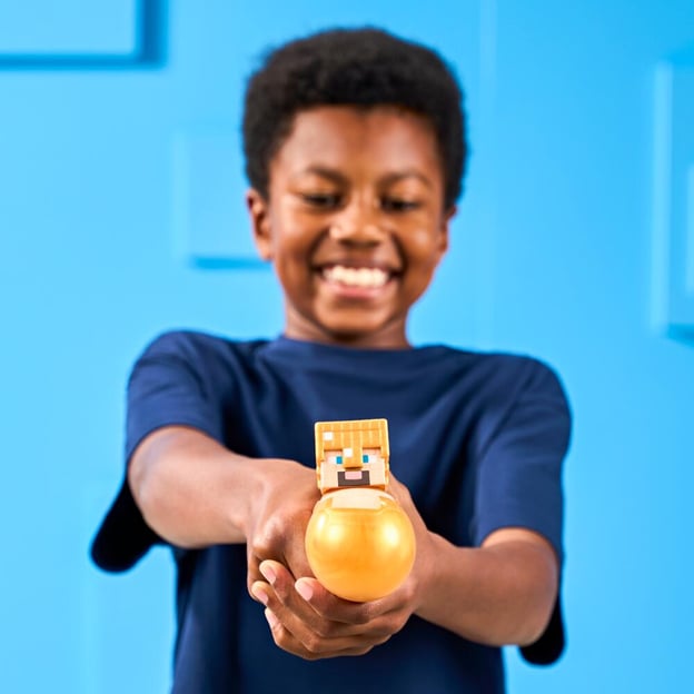 Young boy squeezing a Goo Jitzu Minecraft S4 Hero Pack Gold Armor Steve toy.