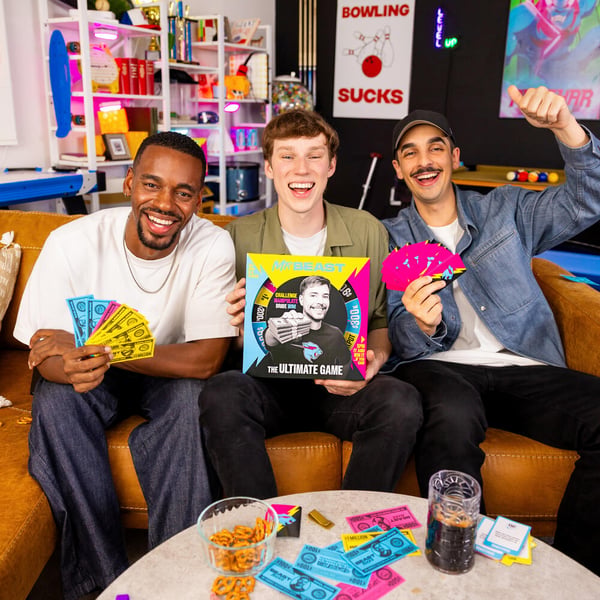 Three men holding the MrBeast Ultimate Game.
