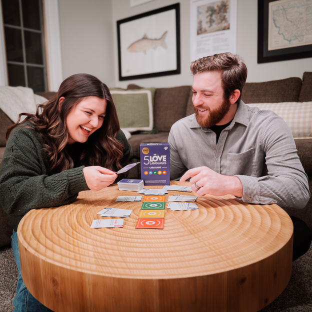 A couple playing the 5 love languages card game at a coffee table. 