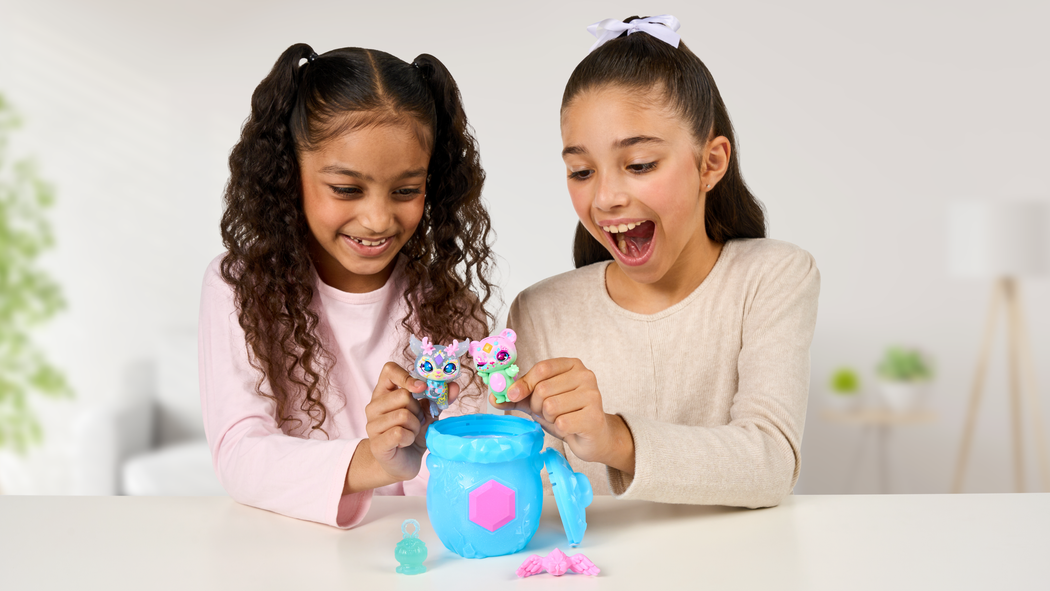 Two girls playing with Magic Mixies Mixlings toys with a small blue cauldron.