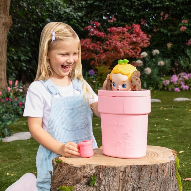 Young girl lokking at her pink Luvibubs Cheerful Charlie toy. 