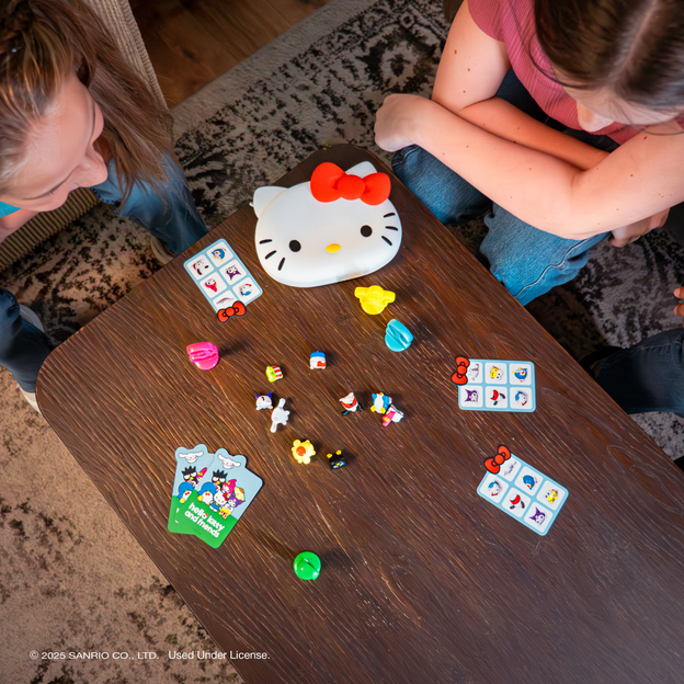 A bird's eye view image of a mother and daughter playing the Hello Kitty and Friends Reach for the Stars Game around a coffee table.