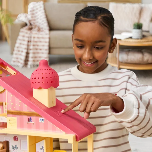 Little girl pressing her finger on the roof of a Bluey Surprise Home Playset.