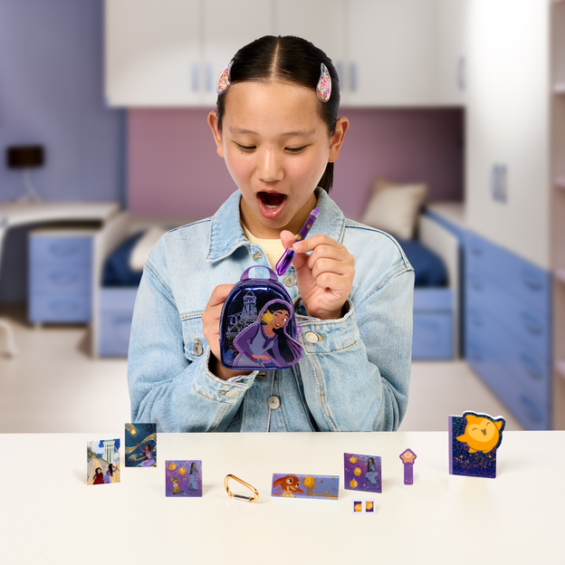 Girl putting stationary into a Disney themed Wish mini backpack.