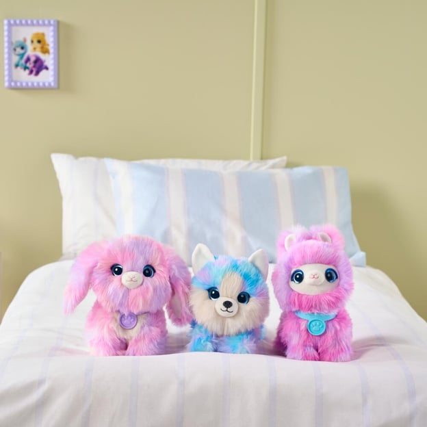Three assorted ScruffaLuvs Tiedye toys sitting on a bed. 