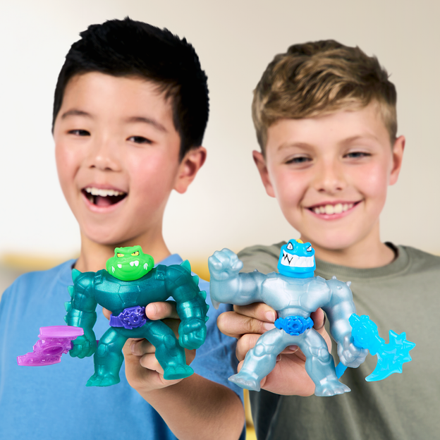 Two young boys holding a blue and green Heroes of Goo Jit Zu toy each. 