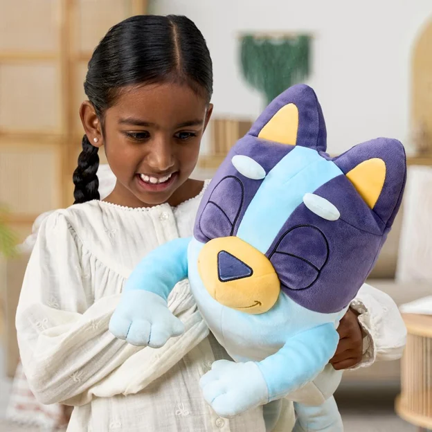 Little girl holding a sleepy Bluey Plush.