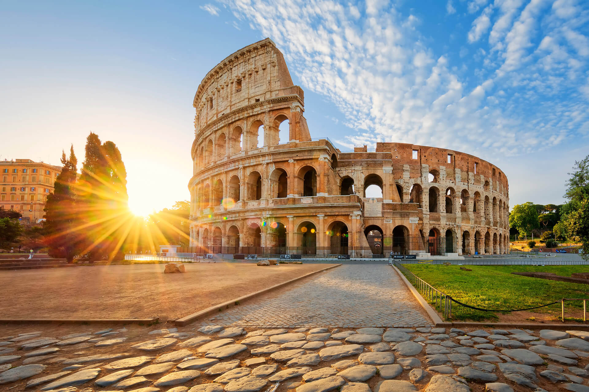 Vista del Coliseo Romano al atardecer, con cielo anaranjado y luz cálida iluminando el histórico anfiteatro en Roma, ideal para inspirar el aprendizaje de italiano con Berlitz