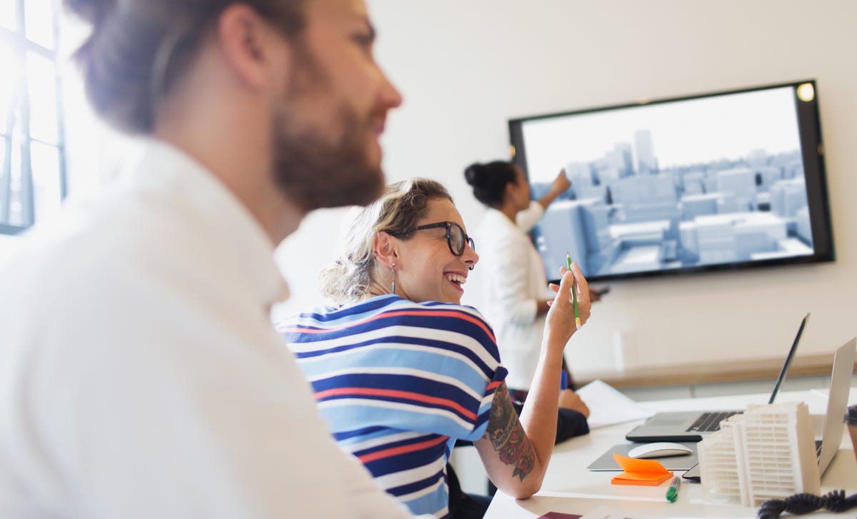Mujer exponiendo frente a un grupo de adultos alegres