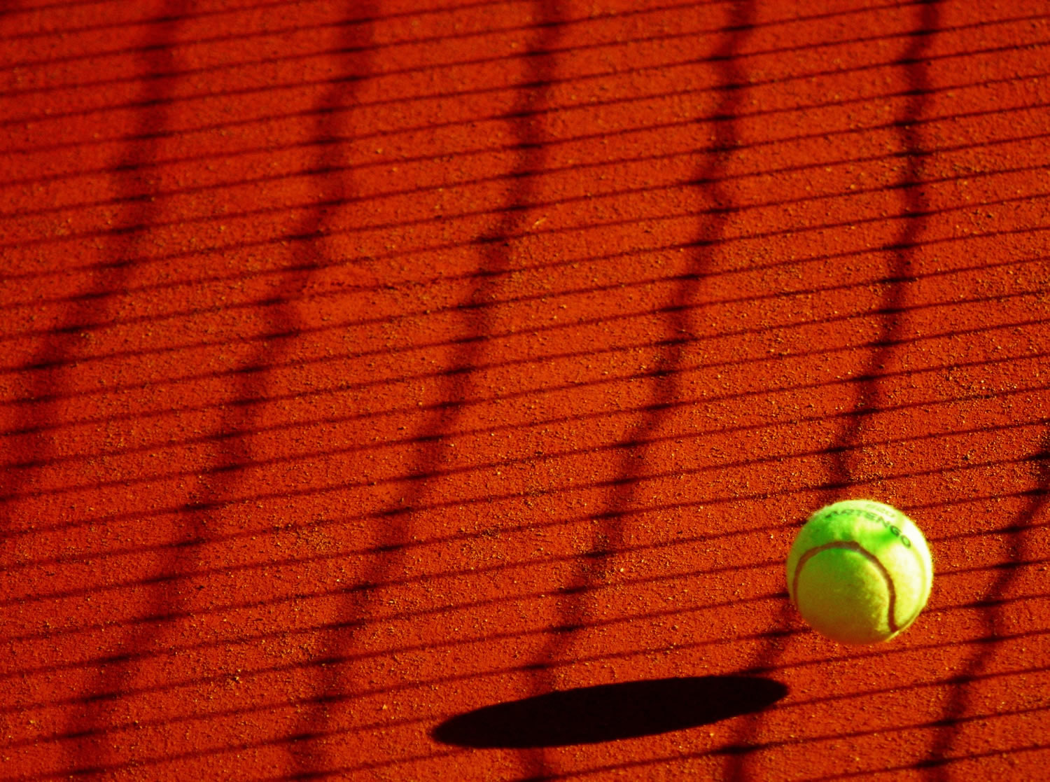 Pelota de tenis sobre cancha de color rojo