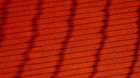 Pelota de tenis sobre cancha de color rojo