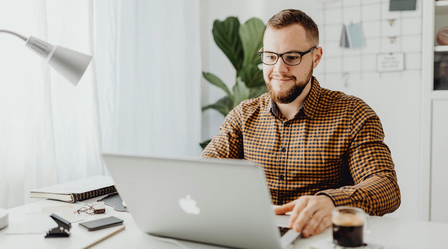 Hombre estudiando con su computadora porque cree en la educación en línea.