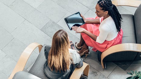 Dos mujeres platicando sentadas en dos sillones