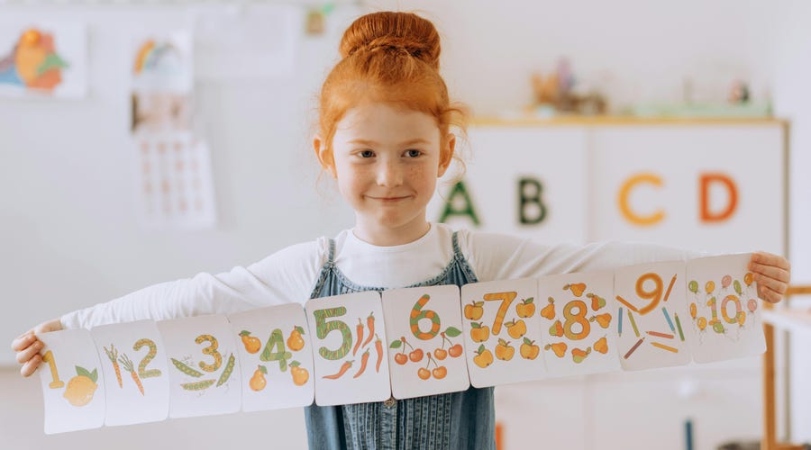 Niña peliroja con cards de los números en inglés para niños.