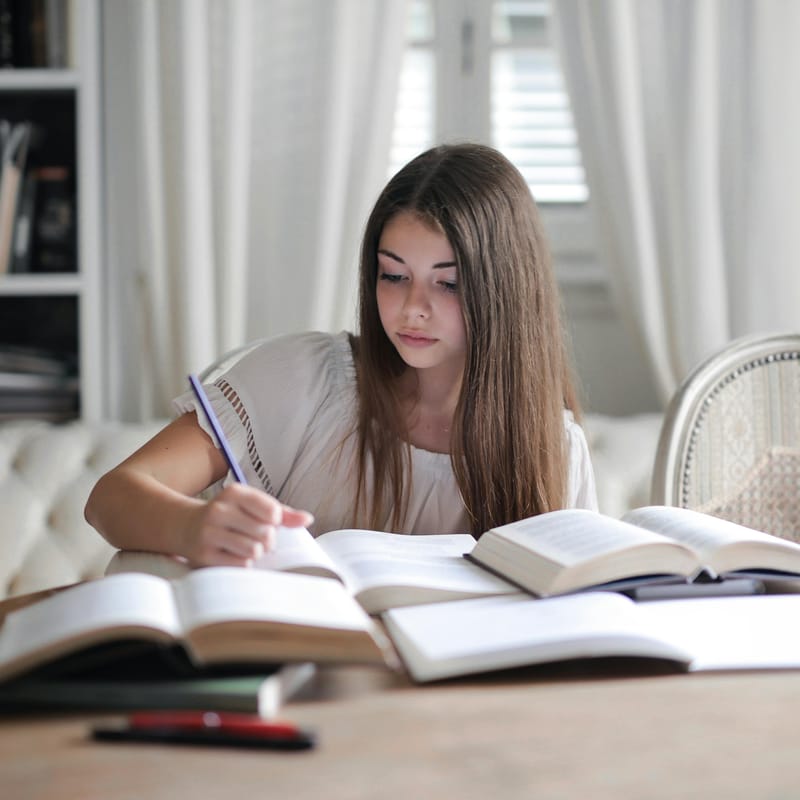 Chica estudiando con libros las opciones de expresiones de cortesía en inglés.