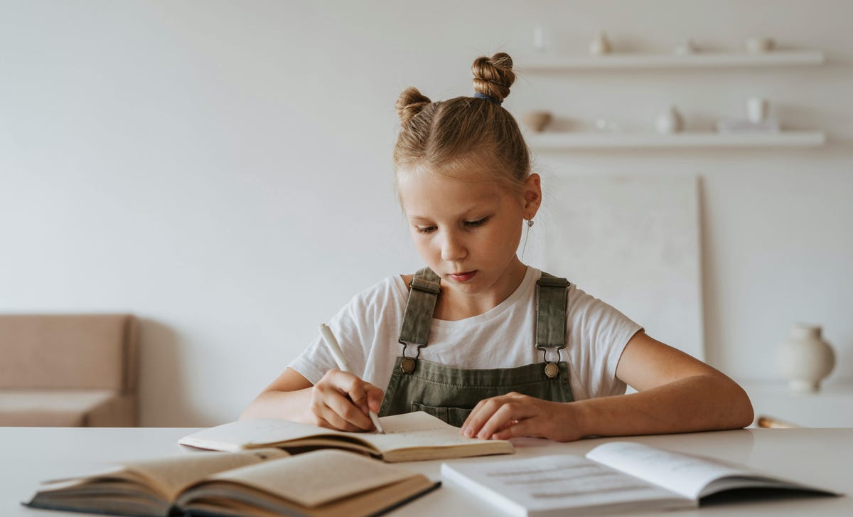 Niña rubio estudiando alemán con su libro de historia.