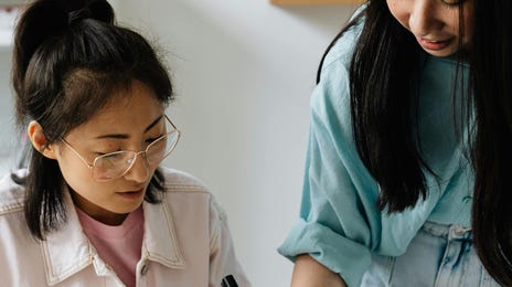 Dos amigas estudian idiomas en clases grupales.
