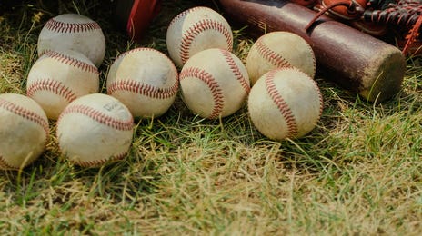 Casco, bat, manoplas y pelotas de béisbol en el campo