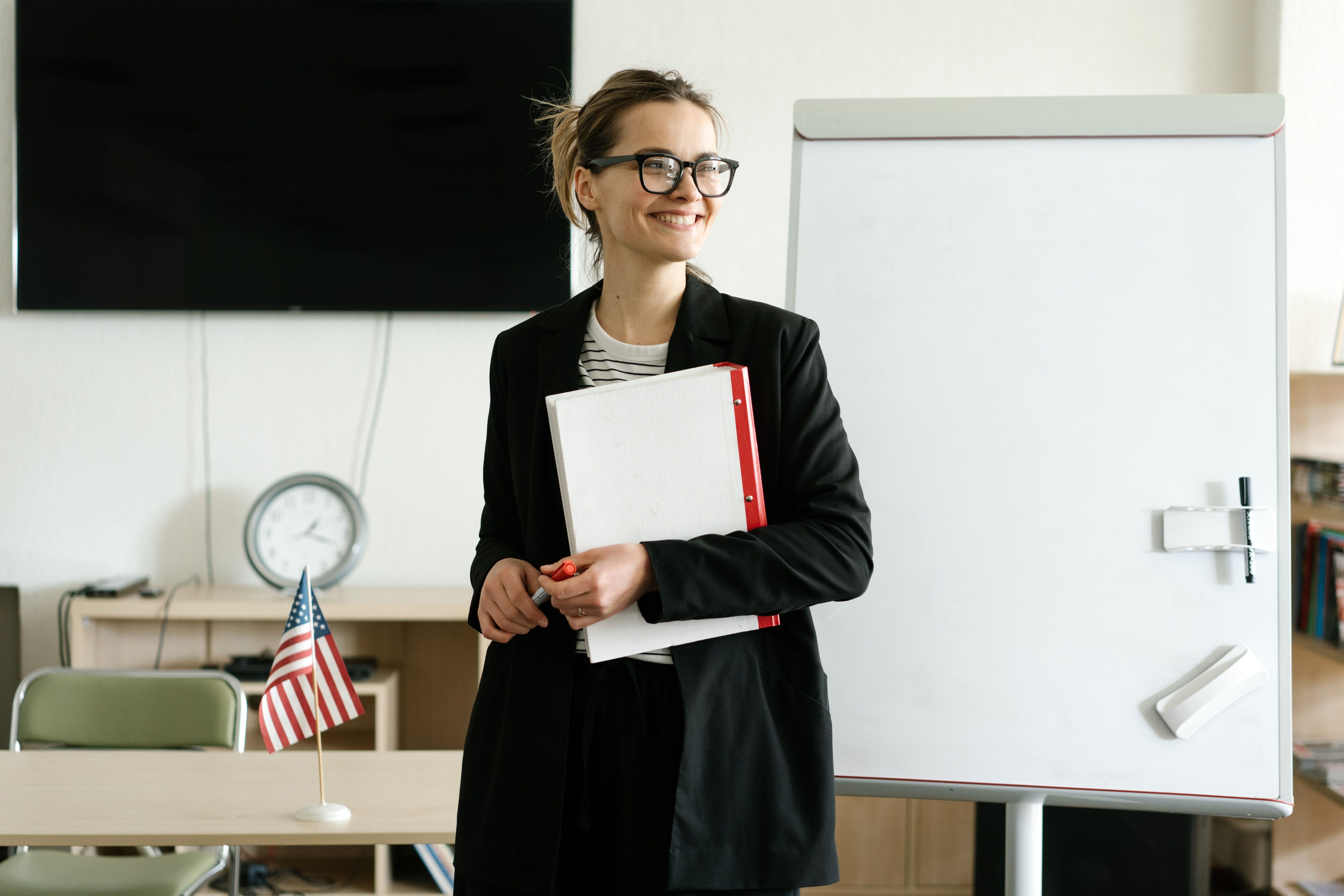 Una maestra sonriendo en un salón de clases para representar una buena profesora de inglés.