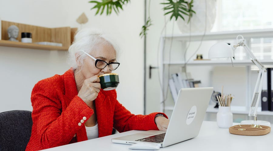 Mujer dueña de una empresa tomando un café mientras busca opciones para el aumento salarial de sus empleados.