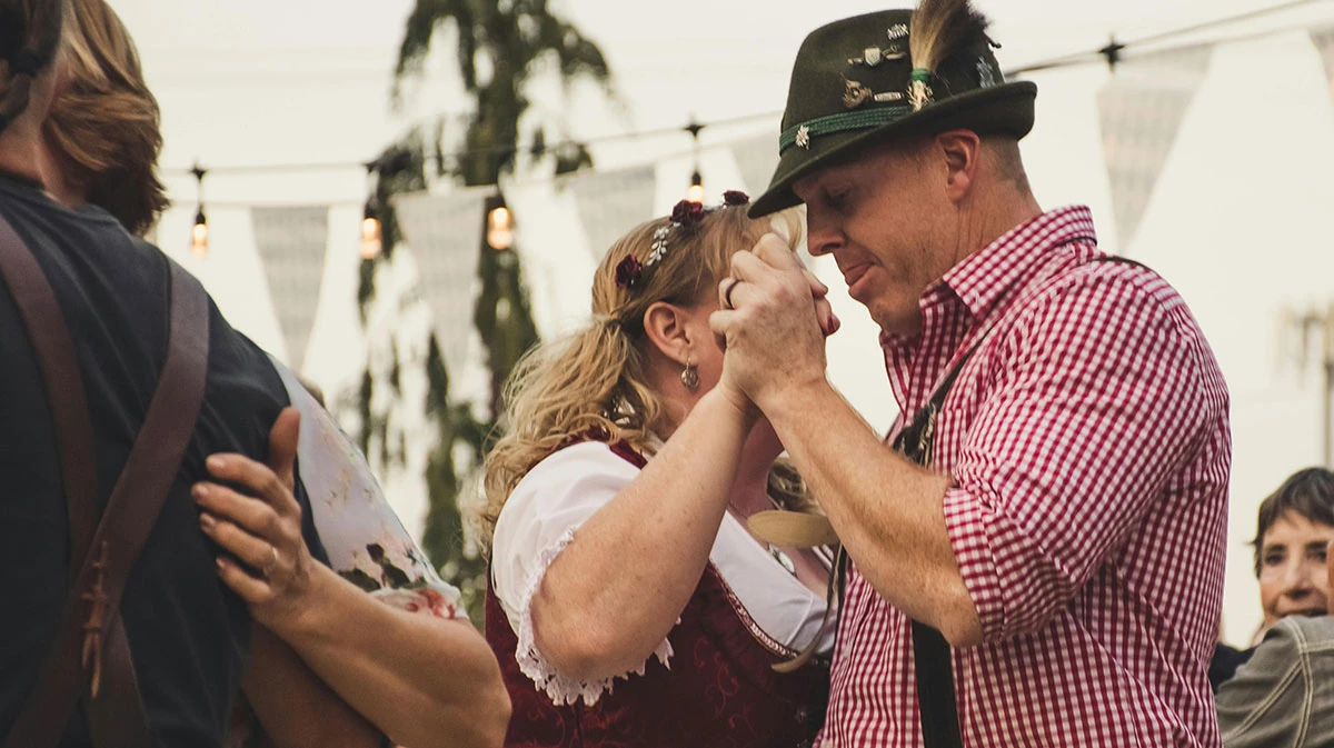 Pareja disfruta de Oktoberfest bailando y platicando en Alemán