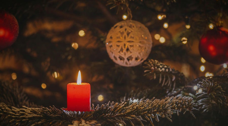 Velita roja y un árbol de Navidad con decoración blanca para la fiesta de Yule.