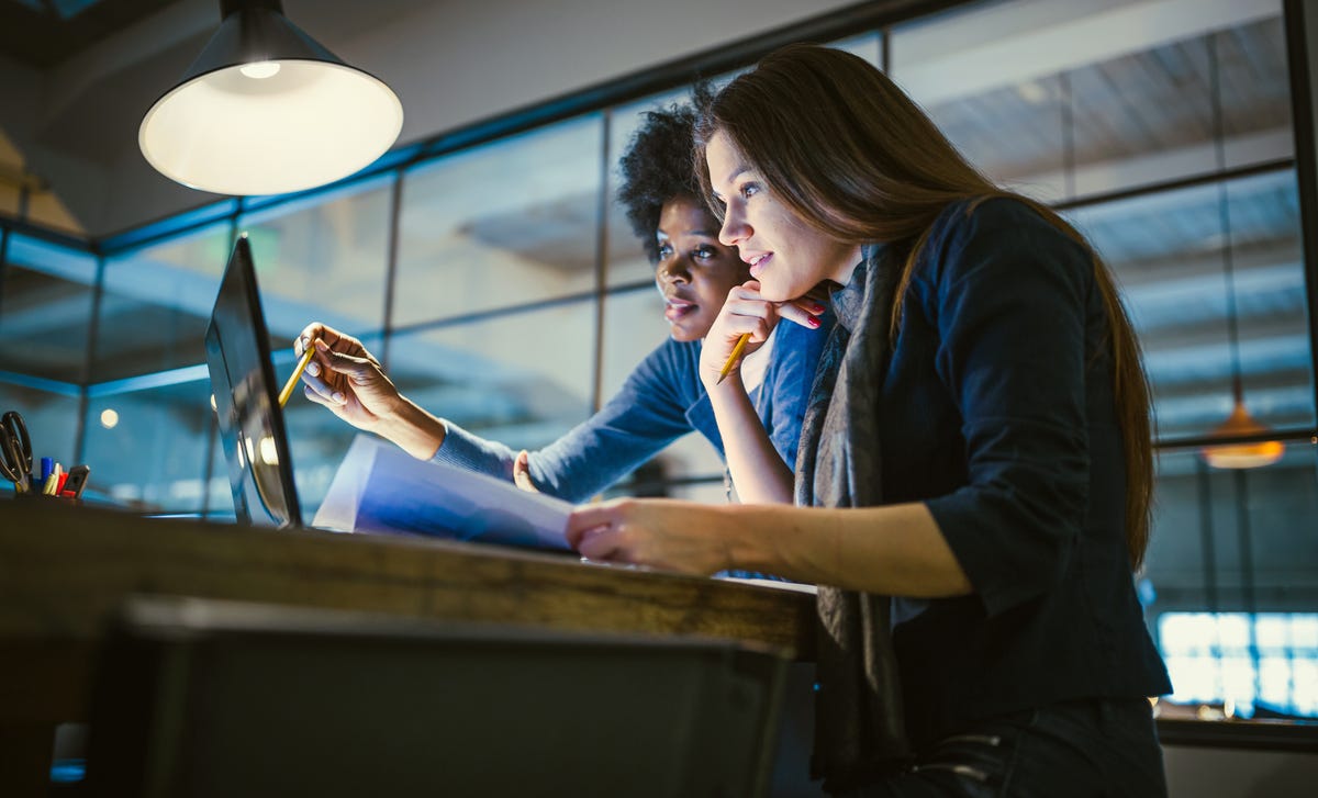 Dos mujeres reunidas observando algo en una computadora