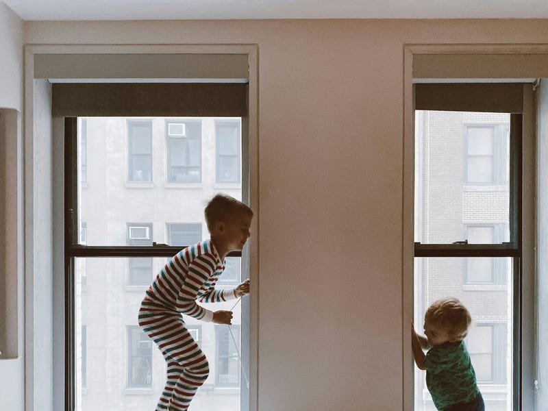Dos hermanos en inglés jugando cerca de las ventanas.