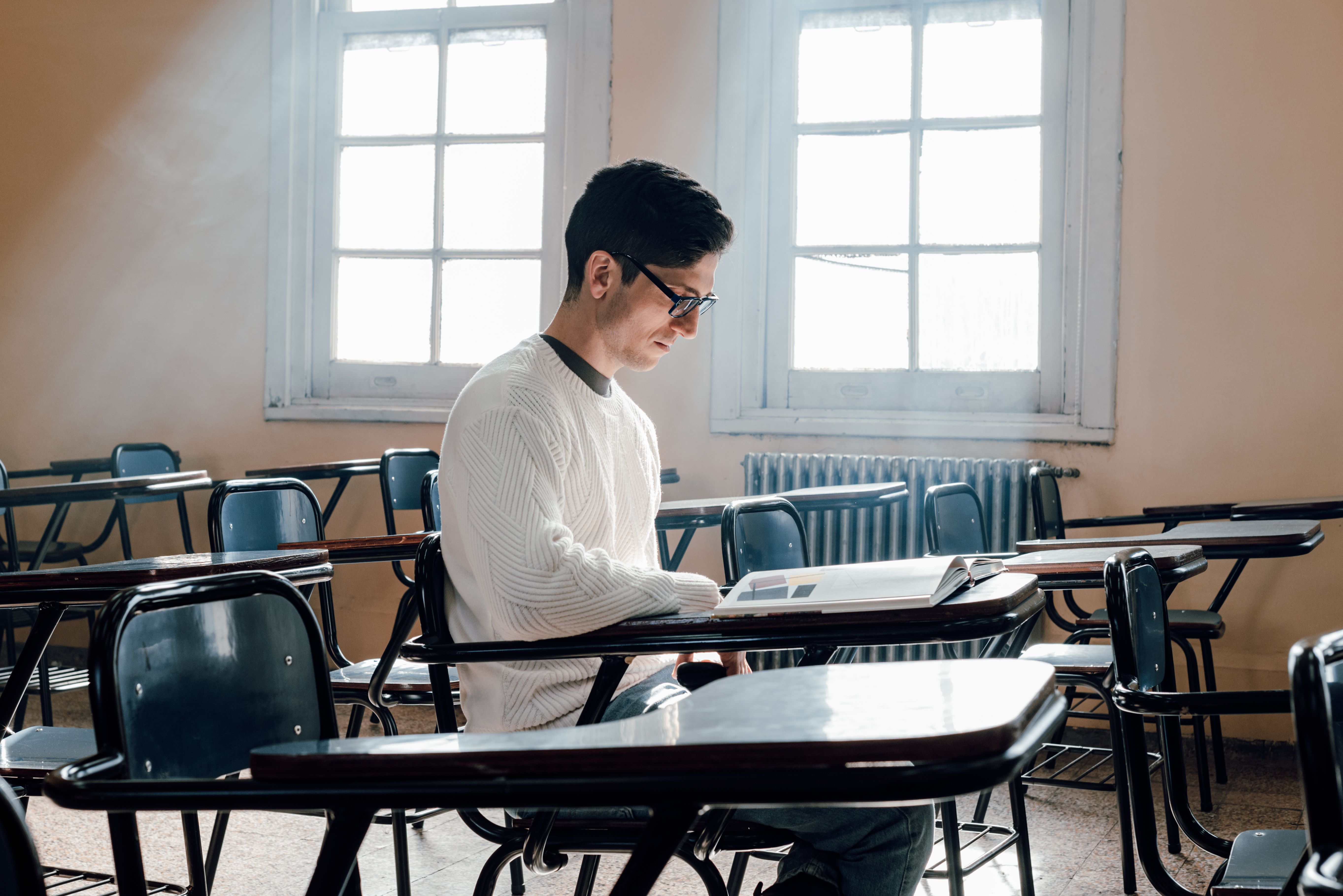 Estudiante en salón leyendo un libro sobre verbos copulativos en inglés.